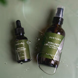 A flatlay photo of SUDTANA’s Bergamot Coconut & Sesame Hair Mask Oil and Bergamot Mint & Turmeric Scalp Revival Treatment with drops of the lightweight, fast-absorbing oils. Perfect for nourishing and revitalising hair and scalp.