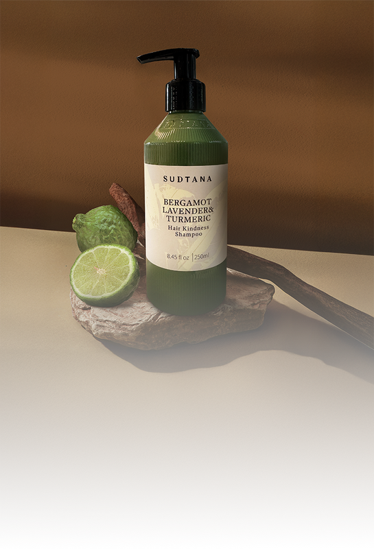 SUDTANA’s Hair Kindness Shampoo with Bergamot, Lavender & Turmeric, featured with halved bergamot on natural stone.