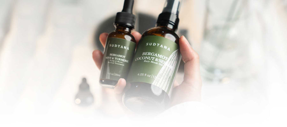 Model holding SUDTANA’s Bergamot Coconut & Sesame Hair Mask Oil and Bergamot Mint & Turmeric Scalp Revival Treatment, showcasing premium self-care products for healthy, revitalised hair and scalp.
