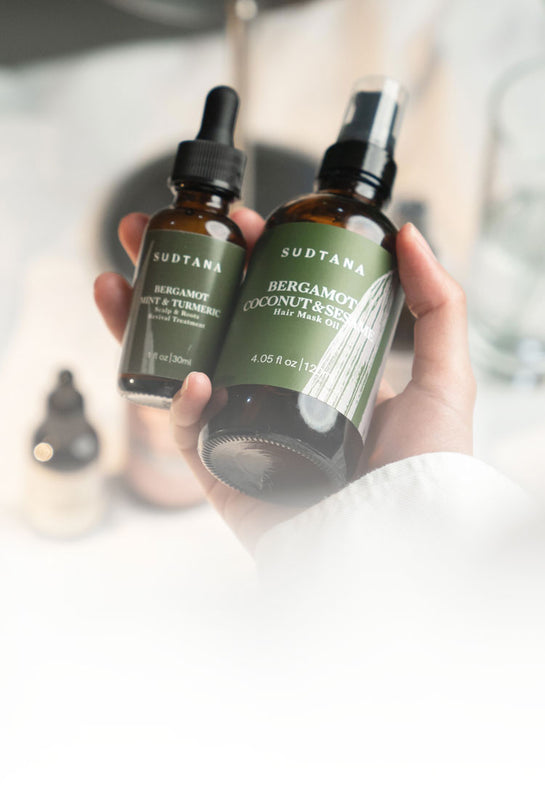 Model holding SUDTANA’s Bergamot Coconut & Sesame Hair Mask Oil and Bergamot Mint & Turmeric Scalp Revival Treatment, showcasing premium self-care products for healthy, revitalised hair and scalp.