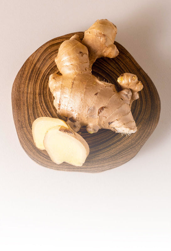 A whole Organic Thai ginger and its slices sustainably sourced from small local farms, a key natural ingredient in clean beauty and spa-grade skincare.